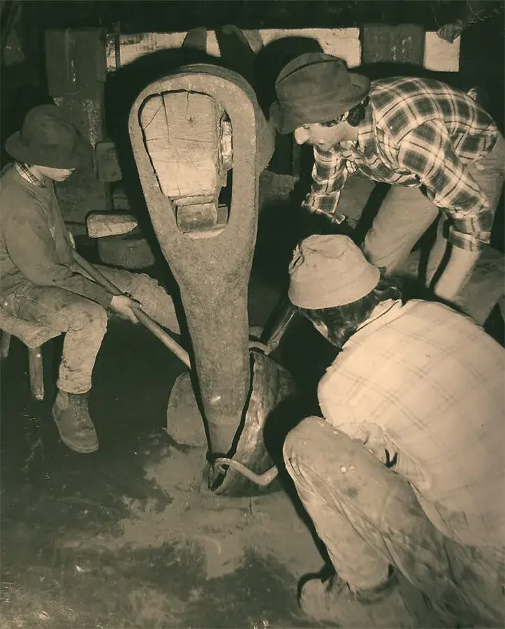 foto in bianco e nero di Osvaldo Pavoni mentre lavora una pentola al maglio